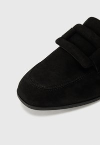 Černé semišové mokasíny s kulatou špičkou a dvojitým páskem. Šití podél stran zvýrazňuje elegantní design.
