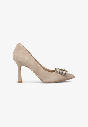 Beige Wildlederschuh mit hohen Absätzen, spitzer Zehenpartie und einer dekorativen, mit Edelsteinen verzierten Schnalle am Rist. Design mit Stiletto-Absatz für erhöhte Statur.