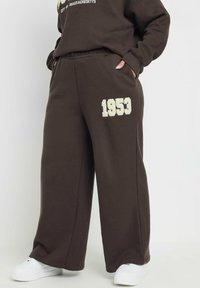 Bruna sweatpants med resårlinning, med en ljusfärgad "1953" tryck på vänster ben, och med en avslappnad passform.