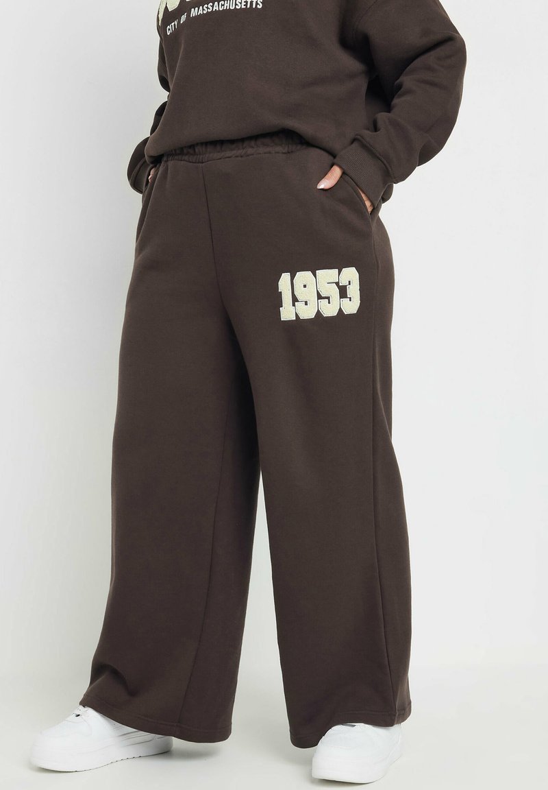 Bruna sweatpants med resårlinning, med en ljusfärgad "1953" tryck på vänster ben, och med en avslappnad passform.