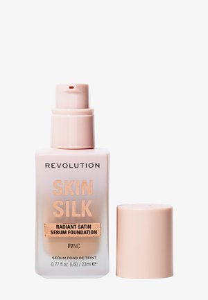 Revolution Skin Silk serum foundation i en frostet glasflaske med en lyserød pumpe. Etiket med gyldent bogstavtryk, som angiver nuancen F7NC.
