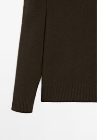 Maglione a maglia marrone scuro con orlo e polsini a costine. Il tessuto sembra morbido e leggero con una superficie liscia.
