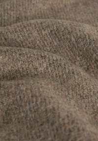 Brązowa dzianina o miękkiej, teksturowanej powierzchni i subtelnych odcieniach koloru, przedstawiona na zbliżeniu z fałdami.