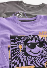Due felpe girocollo: una lavanda con design grafico nero e testo arancione; una grigia scura con testo bianco e elemento di design viola.