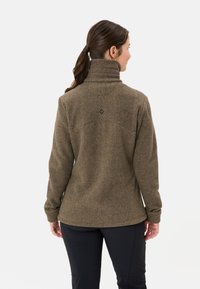 Giacca in pile marrone con collo alto, dettagli sulla cucitura posteriore e sottili accenti neri. La texture appare morbida e calda.