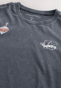Gray cotton T-shirt featuring a decorative Christmas ornament graphic and a "Merry Xmas" print with playing cards on the front.