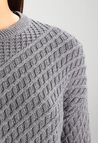 Grauer Strickpullover mit strukturiertem Rautenmuster, mit geripptem Rundhalsausschnitt und weichem, grobem Garn.