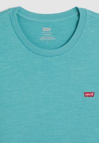 Turkis bomull T-skjorte med runde hals og korte ermer. Har en liten rød Levi's-logo-lapp på venstre bryst.