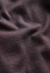 Stoffprobe in tiefem Lila mit einer sanften Textur, die eine leicht zerknitterte Oberfläche und ein dezentes Webmuster aufweist.