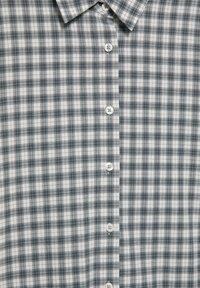 Srajca s ovratnikom, sivka-z belim karo vzorcem in navpično vrsto belih gumbov na sredini spredaj.
