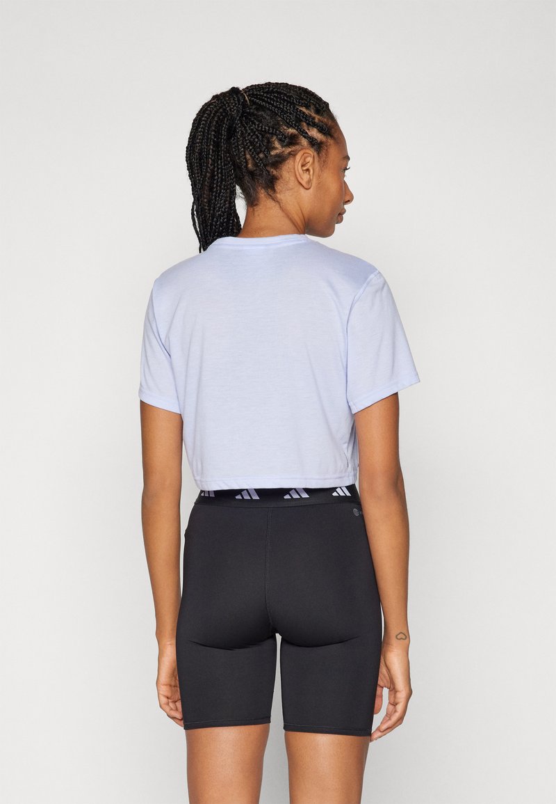 Camiseta de corte cropped en azul claro combinada con shorts de ciclismo negros de cintura alta, que cuentan con una banda elástica con un patrón de logo.