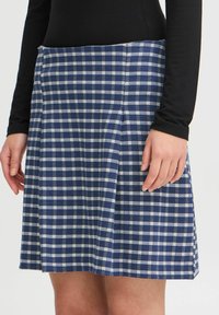 Jupe vichy en bleu marine et blanc, dotée d'un design plissé, réalisée en tissu texturé, avec une taille ajustée et un ourlet droit.