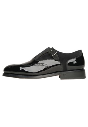 Czarny męski but wizytowy z skóry licowej i zamszu, z klamrą typu monk strap oraz zdobieniami brogue, przedstawiony z boku na białym tle.