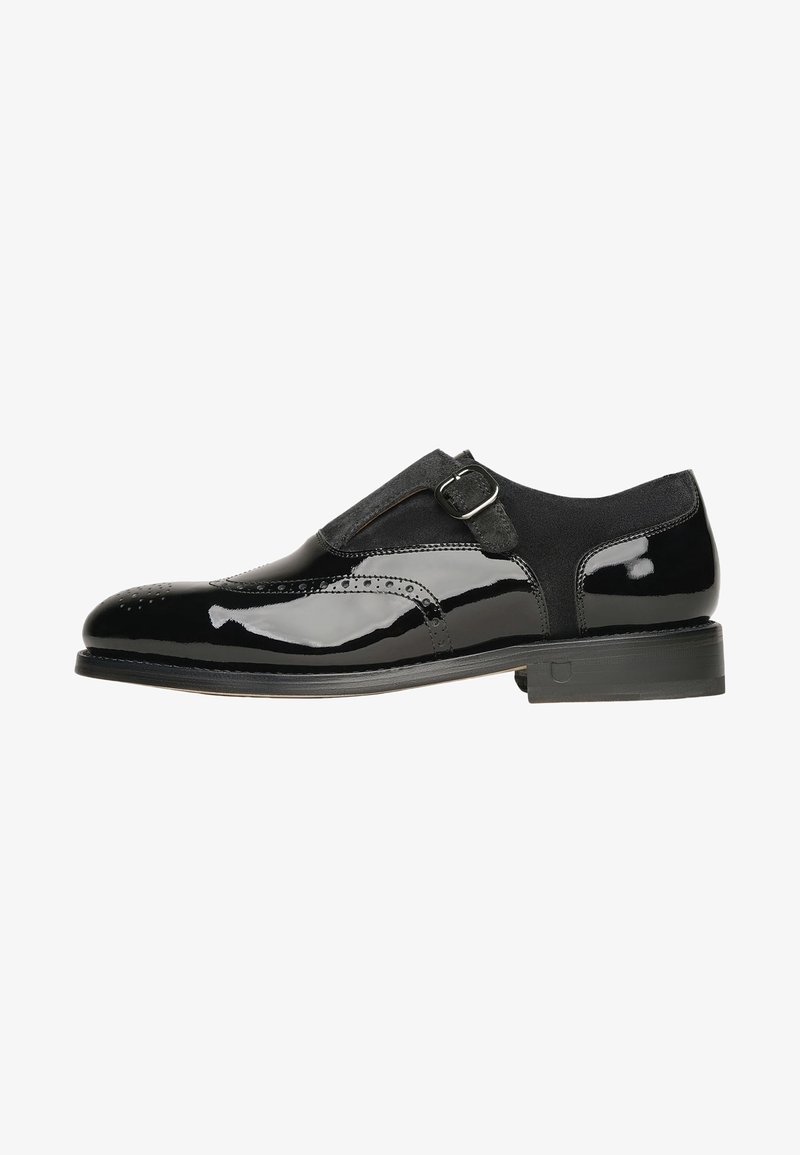 Chaussure habillée pour homme en cuir noir et daim avec boucle à bride de moine et détails brogues, présentée de profil sur fond blanc.