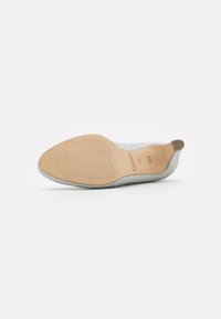Chaussure à talon haut argentée avec une semelle beige, un bout pointu et un petit embout de talon en caoutchouc, étiquetée Gabor taille 41 1/3 Fabriquée au Portugal.
