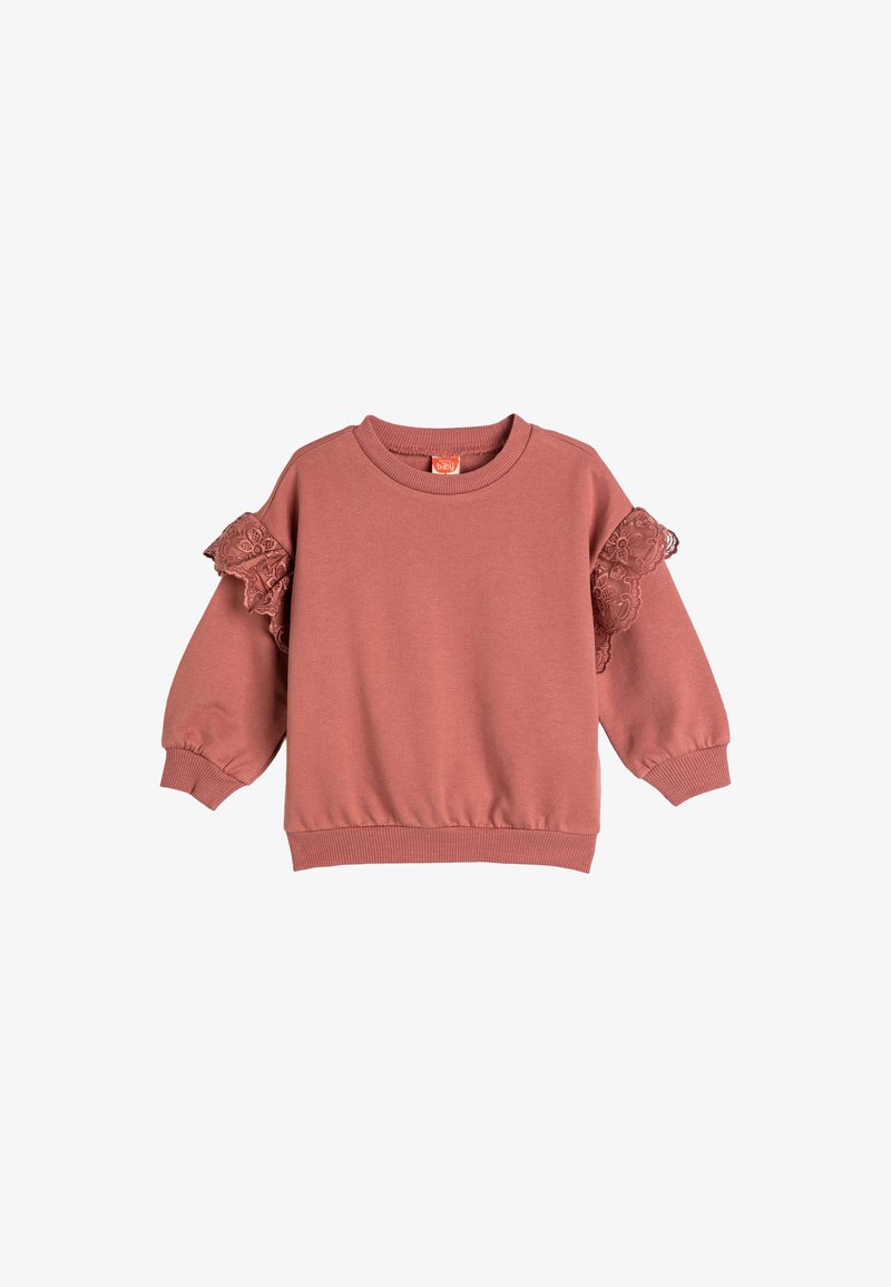 Sweatshirt rose avec des manches longues, des poignets et un ourlet côtelés, et des accents de volants en dentelle sur les épaules. Fabriqué en tissu doux.