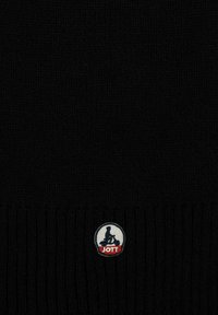 Berretto in maglia nero con orlo a coste, caratterizzato da un patch circolare con un logo nei colori bianco, blu e rosso. Texture morbida.