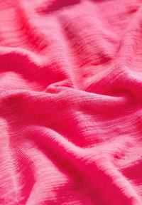 Blødt, tekstureret stof i levende pink, der har et let, let krøllet udseende med subtile linjer og variationer i nuancer.