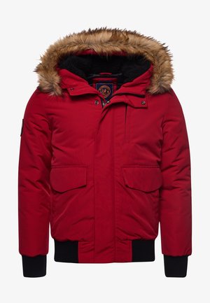 Chaqueta de invierno aislada roja con capucha forrada de piel, puños negros, bolsillos con solapa en la parte delantera y cierre de cremallera.
