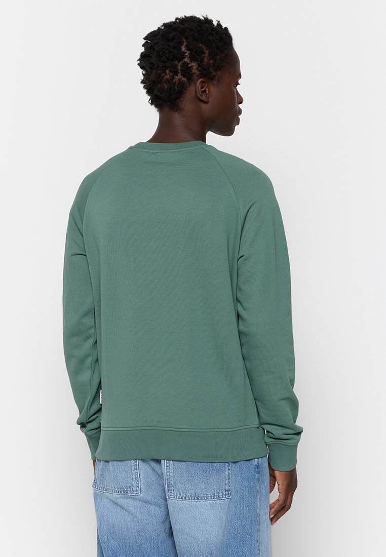 Zielona bluza z okrągłym dekoltem, raglanowymi rękawami i ściągaczami na mankietach. Materiał z mieszanki bawełny o gładkiej teksturze. Luźny krój.
