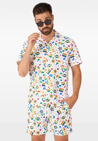 Kurzarmpfshirt mit Knopfleiste und passenden Shorts in Weiß, ausgestattet mit einem lebhaften Muster aus Sternen, Regenbögen und verschiedenen bunten Symbolen.
