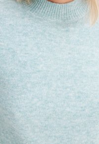 Light blue knitted sweater with a round neckline, textured fabric, and subtle pattern, featuring a soft, cozy finish.