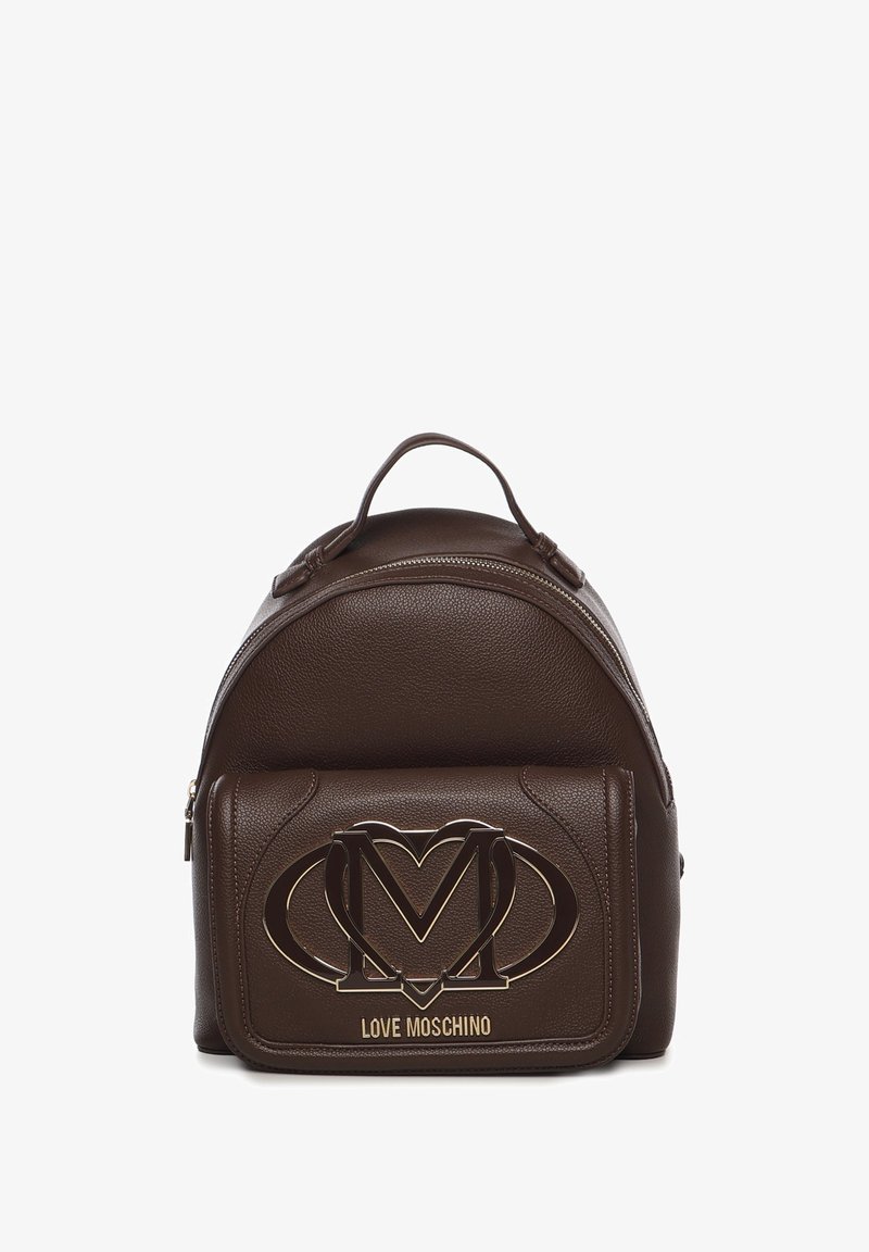 Mochila de cuero marrón con forma redondeada, que cuenta con un bolsillo frontal con un diseño de logo en tono dorado y acentos texturizados.