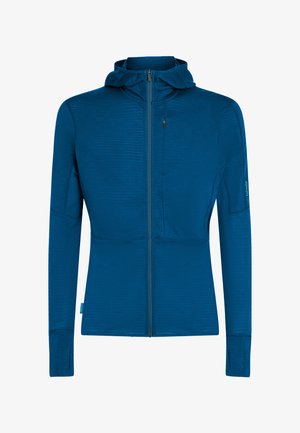 Sininen täysvetoketjullinen huppari, jossa peukaloaukot pitkissä hihoissa, rintatasku vetoketjulla ja istuva leikkaus.