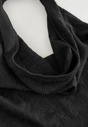 Schwarzer, strukturierter Stoff mit einem zerknitterten Muster, der in einem geschwungenen Design drapiert ist. Das Material wirkt weich und leicht, was die fließende Form unterstreicht.