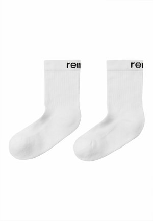 Para gładkich białych skarpetek za kostkę z prążkowaną fakturą i częściowym czarnym napisem blisko górnej krawędzi na każdej skarpecie.