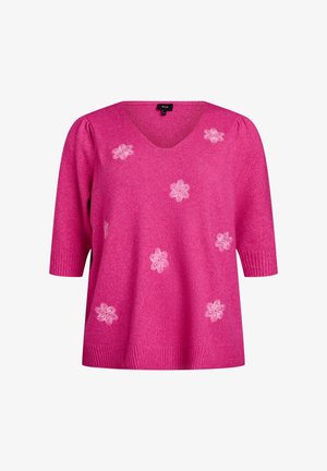 Rožinė megzta palaidinė su V formos iškirpte ir trumpomis rankovėmis. Puošia balti gėlių siuvinėjimai ir banguoti rankogaliai bei apatinė dalis.