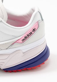 Adidas sneakers med en vit mesh-övre del med rosa accenter, texturerad grå överdel och en flerfärgad klumpig sula.