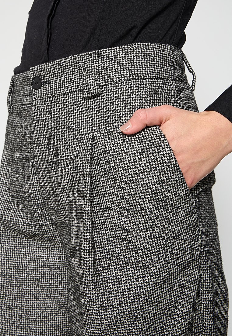Grau karierte Hose mit strukturiertem Finish, seitlichen Taschen und Knopfverschluss. Der Taillenbund ist tailliert für eine schmale Passform.