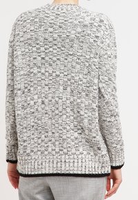 Stickad tröja med ett strukturerat svartvitt mönster, med ribbade muddar och fåll, rund halsringning och en avslappnad passform.