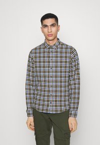 Camisa de cuadros con patrones en marrón, azul y blanco, diseño de botones, con cuello, mangas largas y corte relajado.