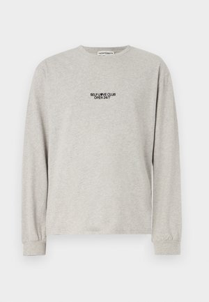 Gray long-sleeve t-shirt in soft cotton, featuring small black text on the front: "SELF LOVE CLUB OPEN 24/7." Simple crew neck and cuffs.
