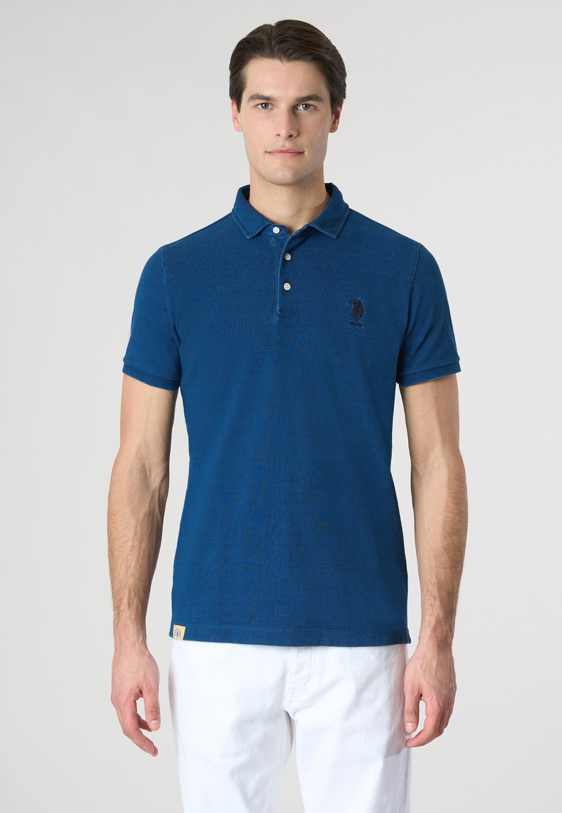 Polo in blu scuro, maniche corte, colletto classico, tre bottoni, con logo ricamato sul petto e etichetta in tessuto sull'orlo.