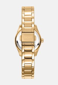 Orologio da polso in metallo dorato con maglie lucidate, cassa rotonda e corona. Presenta un interno argento con marchio DKNY. Finitura liscia e lucida.