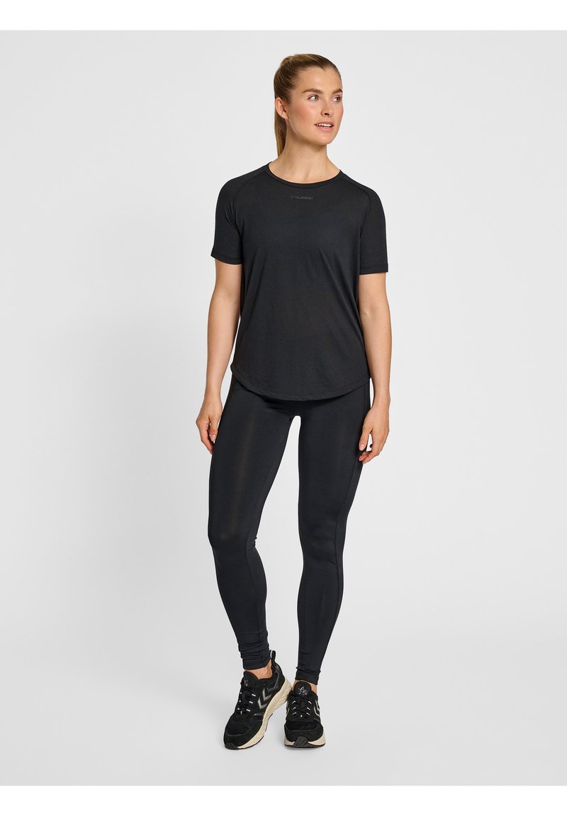 Svart idrottströja och leggings i mjukt, stretchy material. Minimalistisk design med korta ärmar och rundad nederkant; matchas med svarta sneakers.