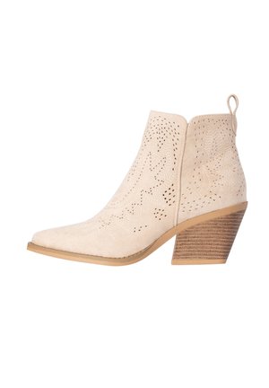 Beige suède enkellaars met geperforeerde decoratieve patronen, spitse neus, aantreklipje en gestapelde houten blokhak.