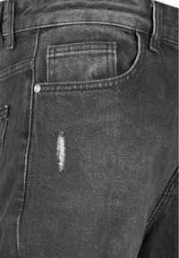 Jeans de mezclilla negra con un parche desgastado, que cuentan con un bolsillo trasero y detalles de costura visibles. La tela tiene una ligera textura.