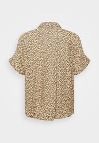 Camicetta beige a maniche corte con motivo a foglie nere e verdi. Vestibilità rilassata con collare e dettaglio a piega sul retro per un maggiore movimento.