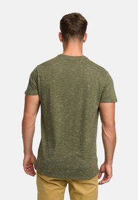 Oliwkowa koszulka z krótkim rękawem o delikatnej teksturze, okrągłym dekolcie i zaokrąglonym dole. Materiał ma melanżowy wzór.