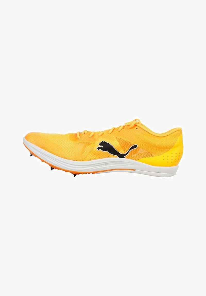 Chaussure de sport jaune avec une tige en mesh respirant, semelle blanche et logo Puma noir. Dotée de six pointes en caoutchouc sous la semelle pour une meilleure traction.