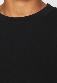 Svart crewneck t-shirt tillverkad av ett mjukt, strukturerat tyg. Har en enkel, ren design med en slät halsringning.