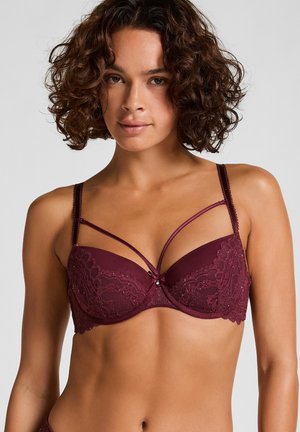 Burgundy lace bra with underwire. Features decorative straps, a central bow, and intricate detailing on cups. Smooth texture overall.