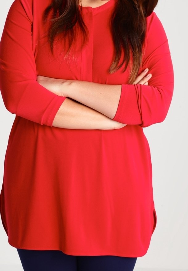 Röd långärmad tunika med rundad halsringning, plisserad frontdesign, sidofickor i fållen och en slät textur.