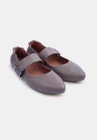 Zapatos de cuero gris con punta afilada, correa ancha con hebilla de metal y un forro interior suave. El diseño de suela plana mejora la comodidad.