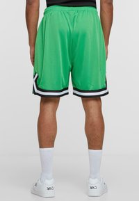 Groene basketbalshorts van meshstof, met een zwart-witte rand aan de zoom, een elastische tailleband en een relaxte pasvorm.