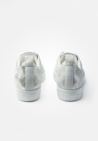 Bílé tenisky s hladkým, metalickým leskem. Zaoblený design se strukturovanými akcenty a polstrovaným patním dílem pro pohodlí.